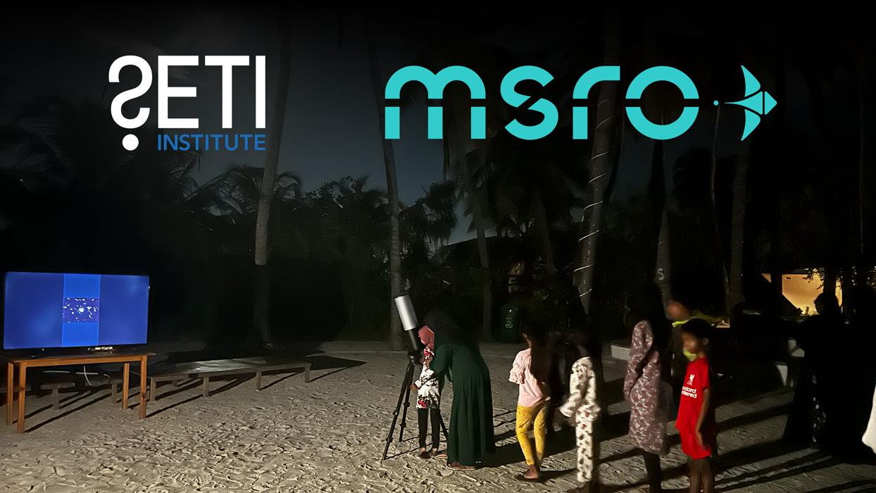 People looking through an eVscope on the Maldivian beach at night.