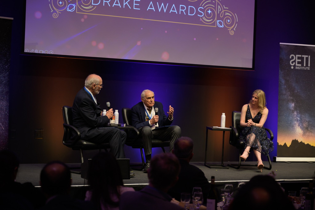 Recipients Dr. Deamer, Dr. Baross, and Awards Host Nadia Drake on stage