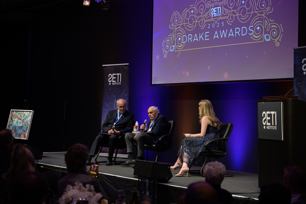 Recipients Dr. Deamer, Dr. Baross, and Awards Host Nadia Drake on stage