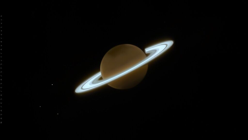Image of a bright beige Saturn with its small moons pictured as tiny dots against the dark background of Space