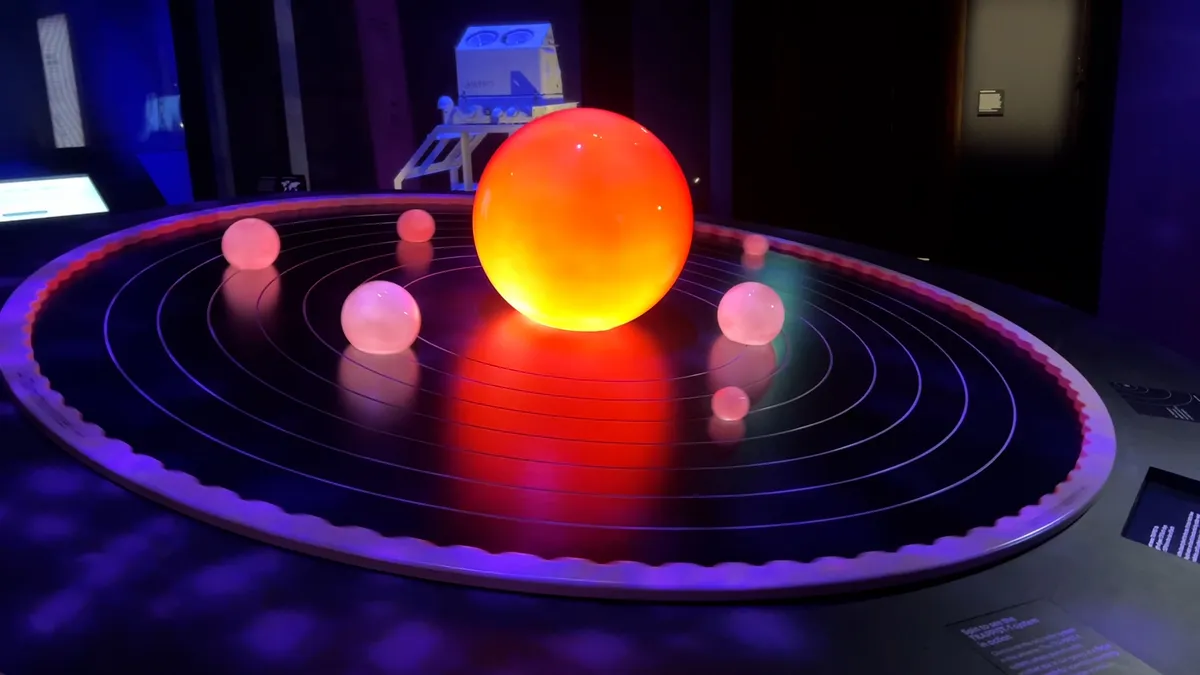 Glowing solar system model with illuminated sun and planets in orbit on a dark display.