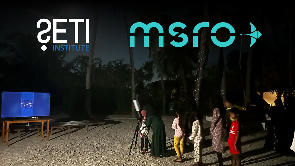 People looking through an eVscope on the Maldivian beach at night.
